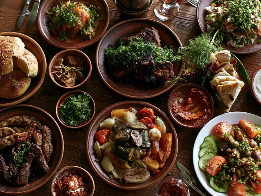 A Georgian spread from above: grilled meat, kebabs, roasted vegetables, herbs and bread